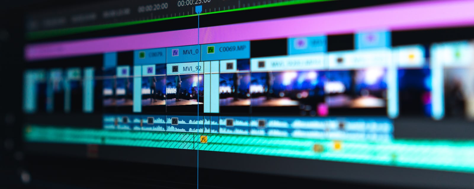 Pla molt de prop d'una línia de temps de muntatge de vídeo en un monitor, amb blocs de color lila i turquesa