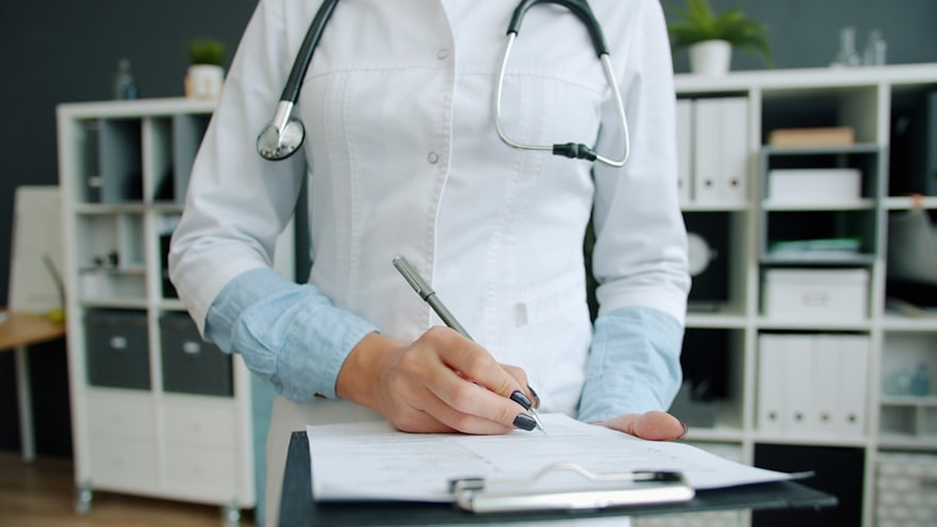 Physician completing medical records at a clinic desk