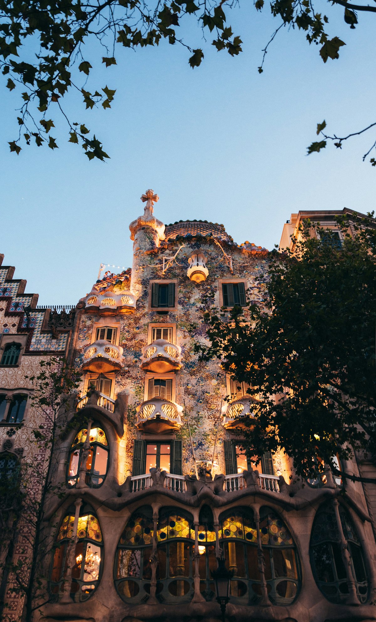Fachada da Casa Batlló ao entardecer, com os seus mosaicos e varandas emblemáticas iluminadas, em Barcelona