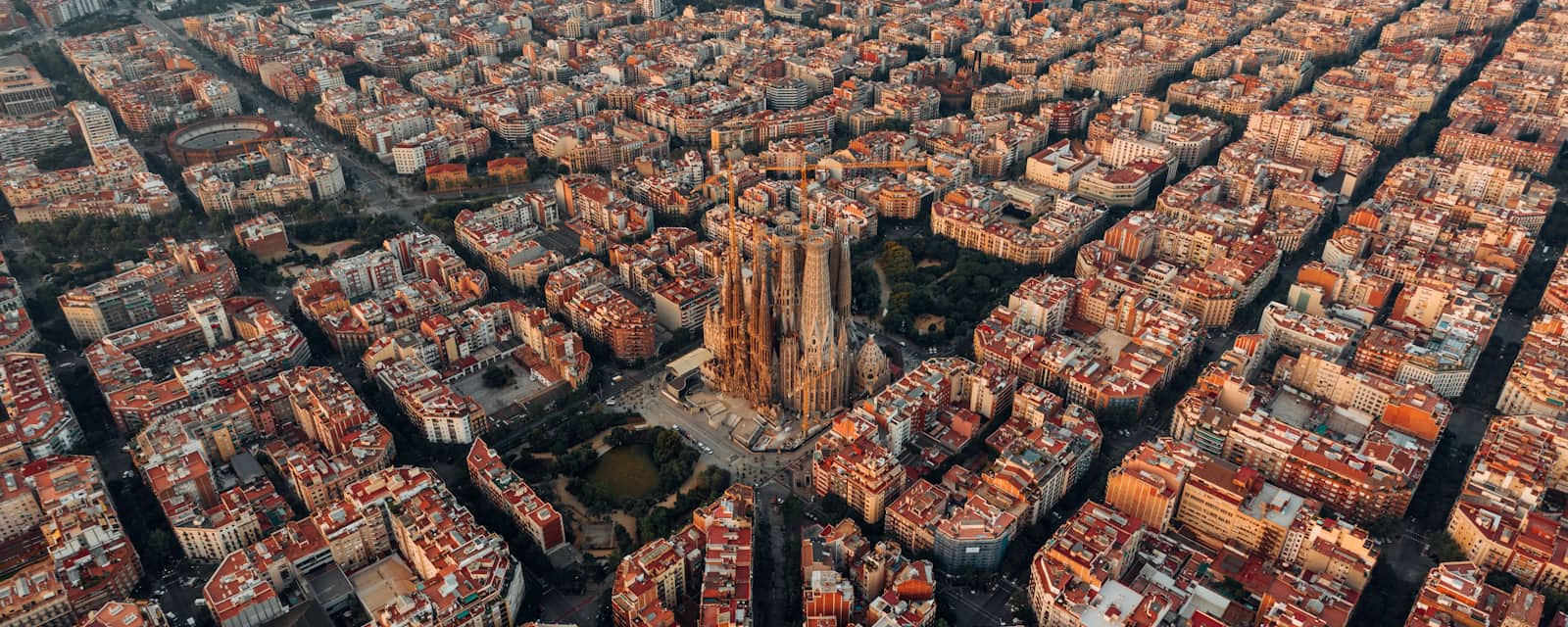 Vista aerea di Barcellona al tramonto con la Sagrada Família al centro della griglia urbana dell'Eixample