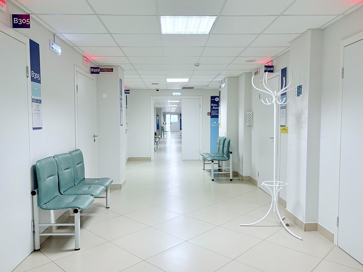 Passadís d'una clínica amb bancs d'espera buits i portes numerades a banda i banda
