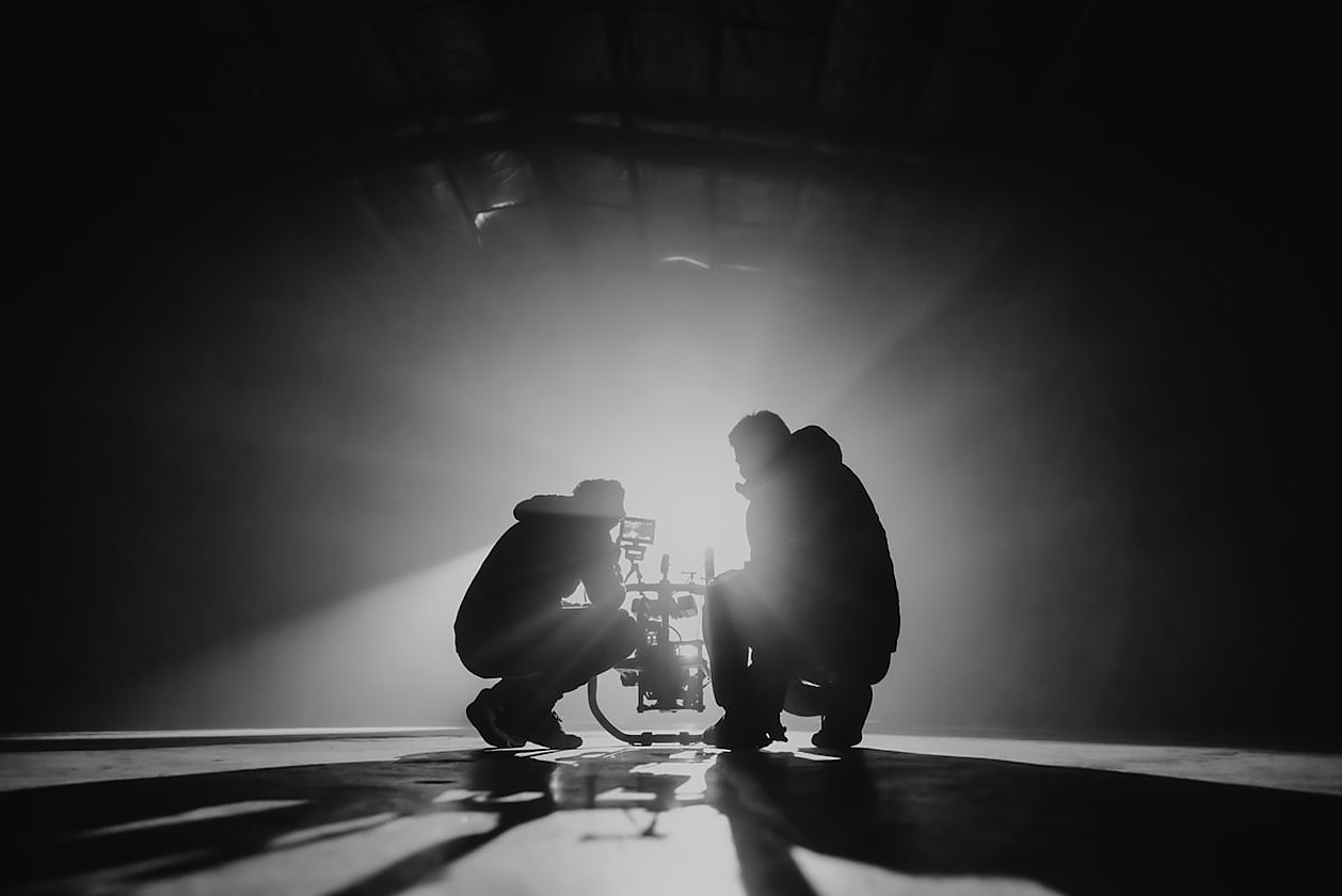 Silhouette eines Filmteams bei einem Dreh mit Kamerarig im Gegenlicht, als Sinnbild für audiovisuelle Produktionen und ihre Lokalisierung