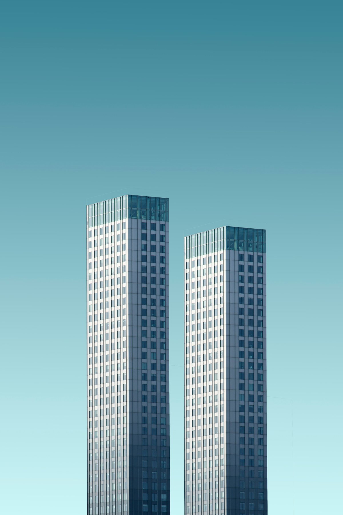 青みがかった空を背景にそびえる、ガラス張りの高層ビル2棟。互いに向き合うように建つそのシルエットが、日本本社とカタルーニャ現地法人という二つの拠点の関係を思わせるイメージ