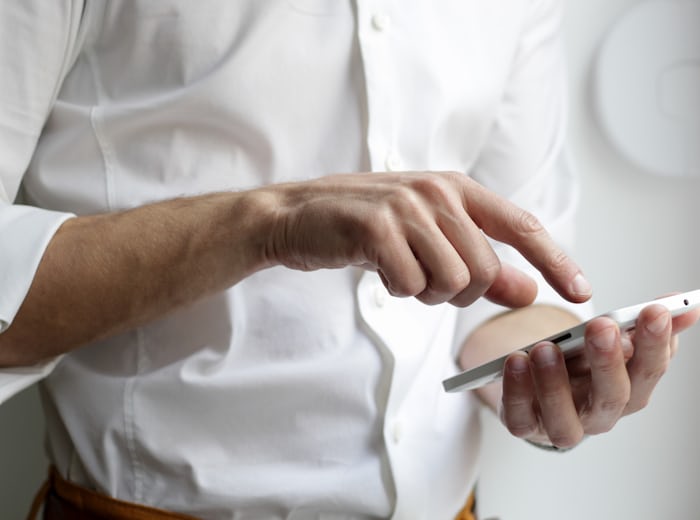Una mà sostenint un telèfon mòbil mentre l'altra hi assenyala la pantalla, imatge que remet a una trucada d'interpretació telefònica